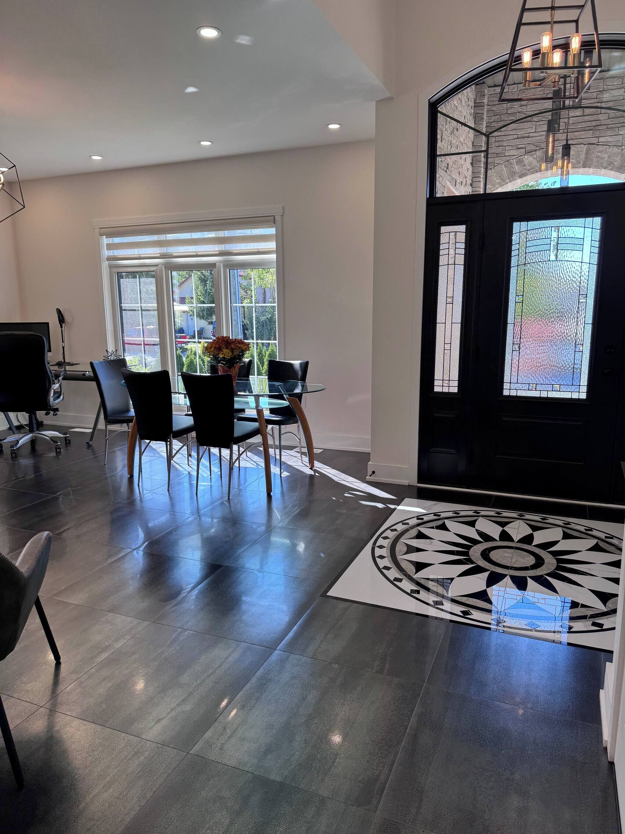 Um interior moderno com área de jantar, uma janela grande e um piso estampado.