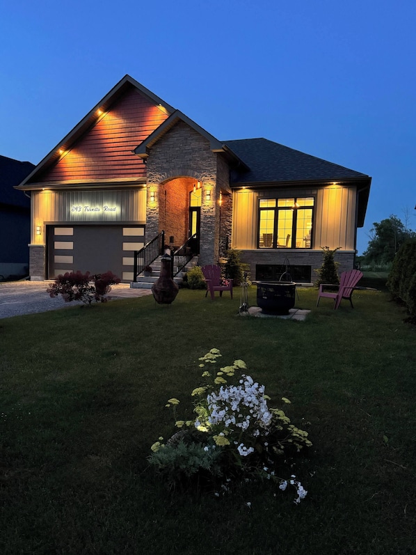 A two-story house with a garage, stone facade, and a well-maintained lawn. - Cozy Lakefront House Retreat For Families&friends (Georgina)
