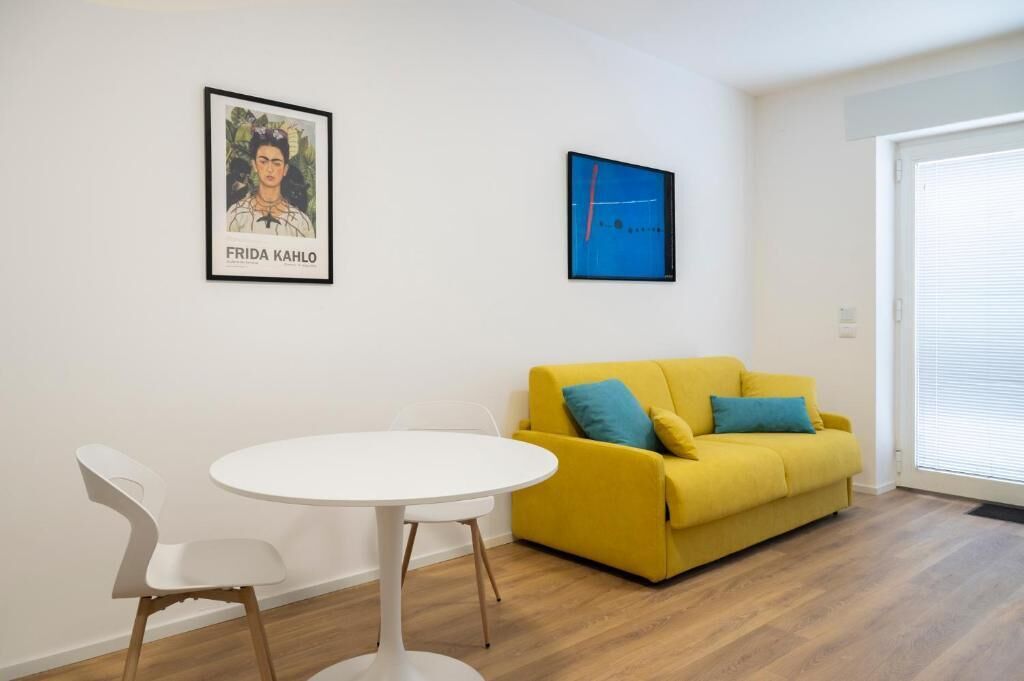 A room with a yellow sofa, a white table, and two chairs.