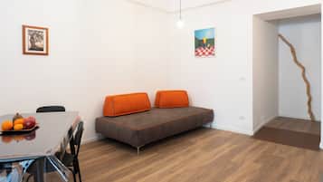 Una habitación moderna con sofá, una mesa de comedor con fruta y obras de arte en las paredes.