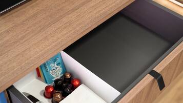A drawer with a black interior, containing a white box, a blue box, and several small containers.