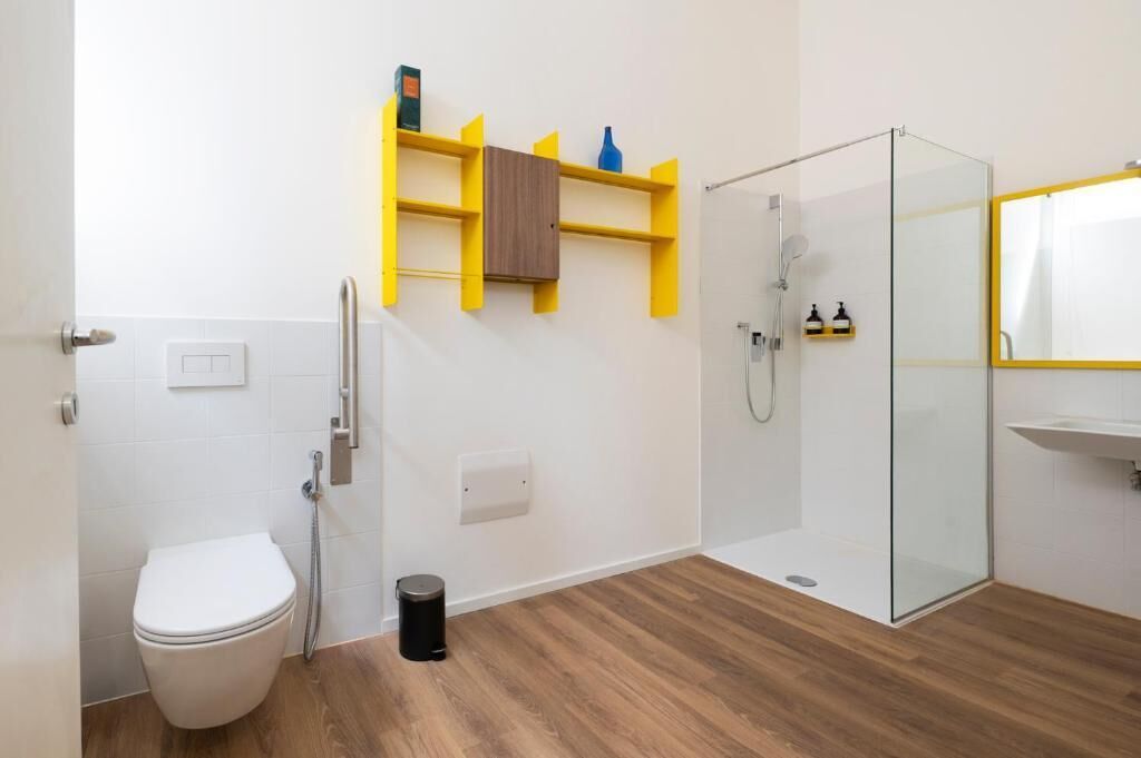 Un baño con inodoro, cabina de ducha de vidrio y piso de madera.