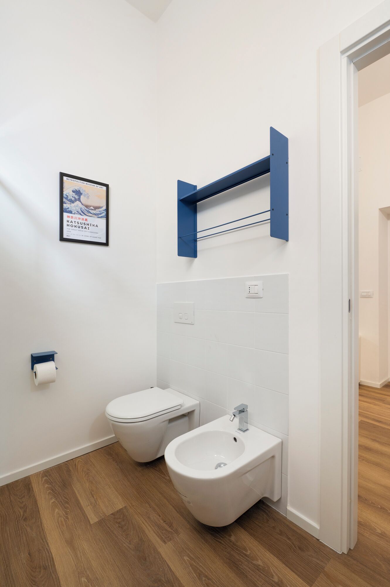 Uma casa de banho moderna com sanita, bidé e um quadro emoldurado na parede.