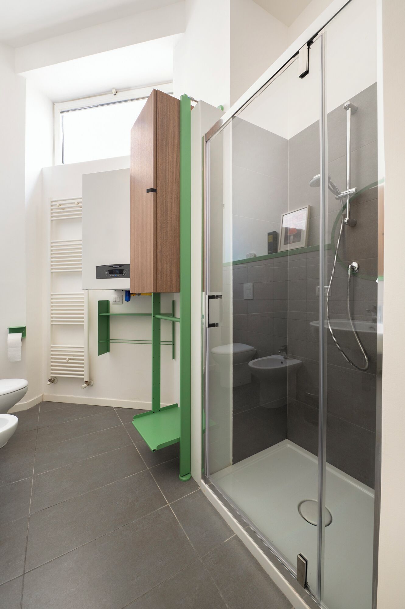 Ein modernes Badezimmer mit einer gläsernen Duschkabine, einer Toilette und einem grünen Stauraum.