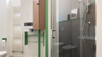 Ein modernes Badezimmer mit einer gläsernen Duschkabine, einer Toilette und einem grünen Stauraum.