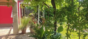 A garden with potted plants and a red building. - Holiday house Vinko (Trogir)