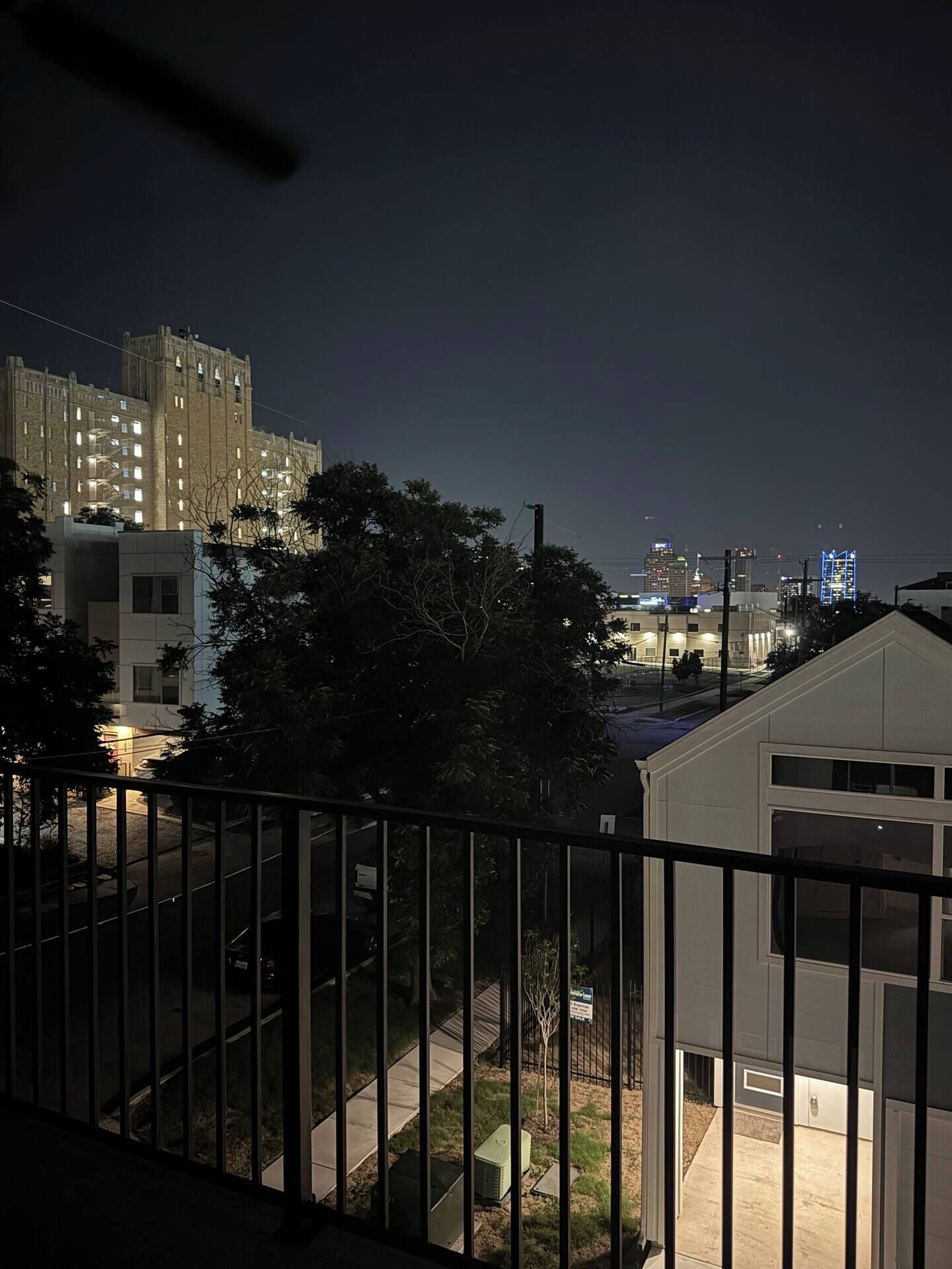 A nighttime view of a residential area with a building featuring multiple windows and a gated entrance.