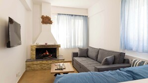 Un salon avec une cheminée, un canapé, une table basse et un téléviseur fixé au mur.
