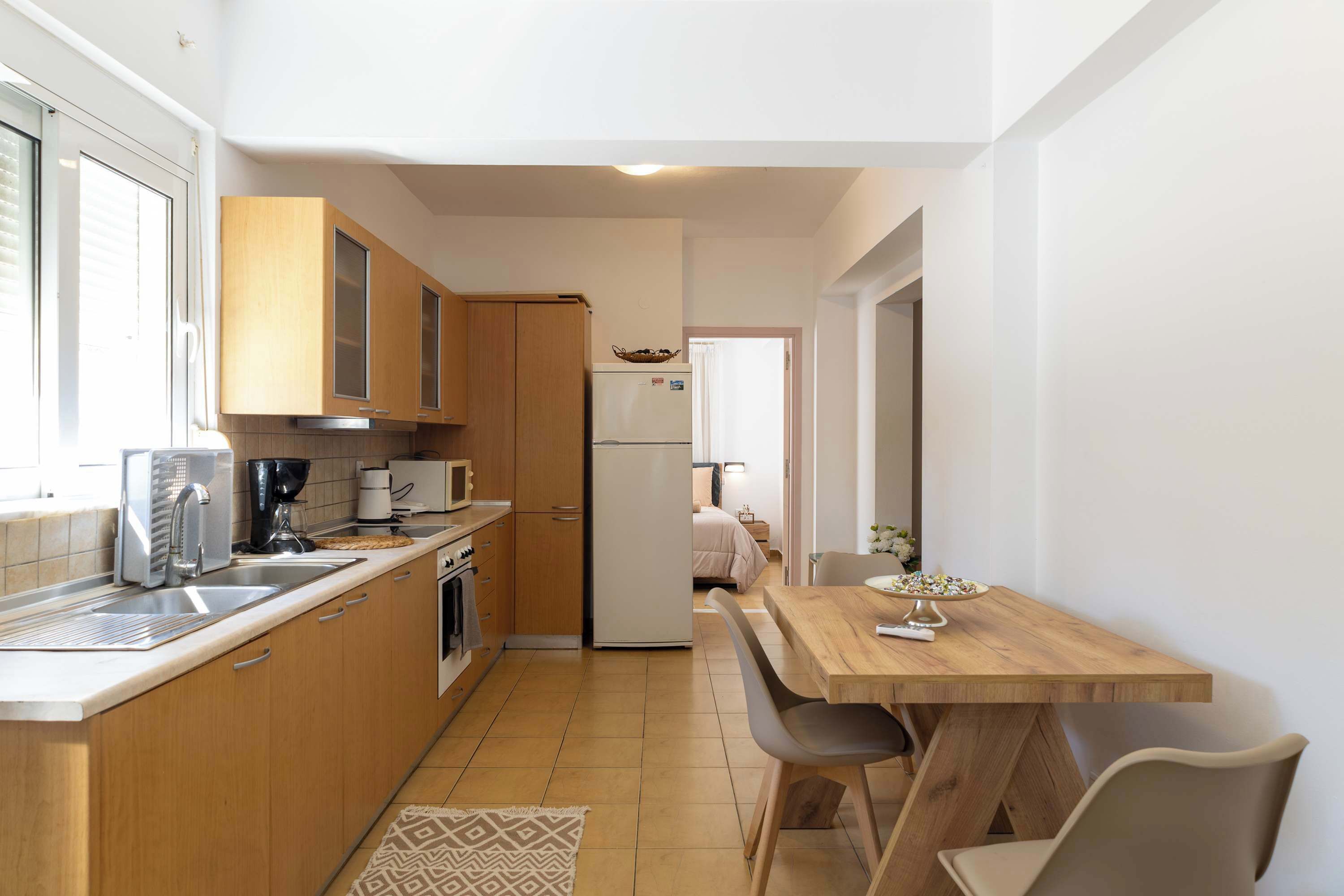Cocina compacta con armarios de madera, refrigerador, microondas y un comedor con mesa y sillas.