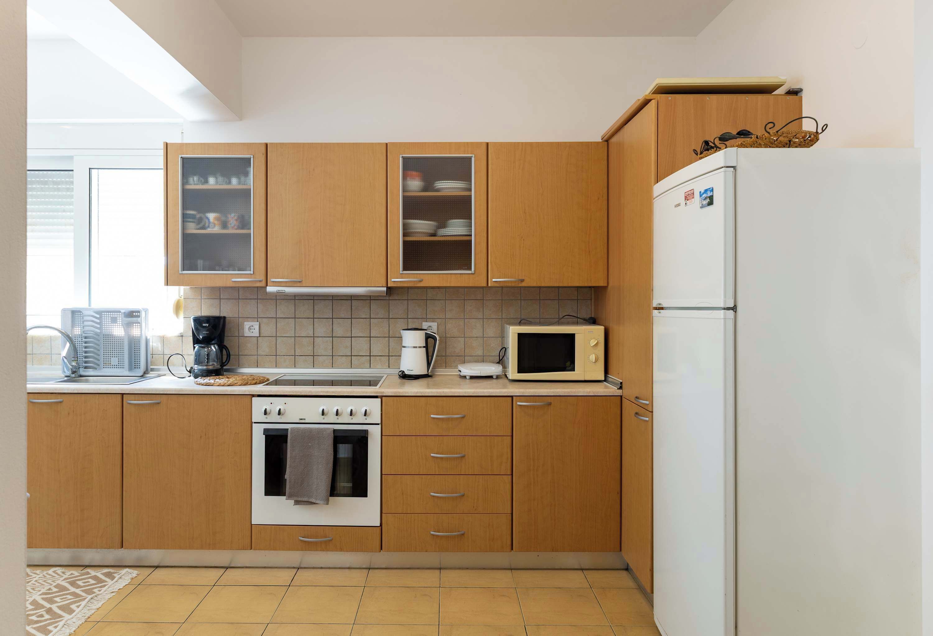 Une cuisine avec des meubles de rangement en bois, un four à micro-ondes, une cuisinière et un réfrigérateur.