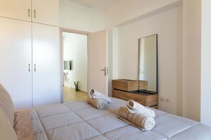 A bedroom with a bed, a wooden dresser, a mirror, and a wardrobe. - Sinani Beachfront Gems Rhodes Jacuzzi Retreat (Pefki)