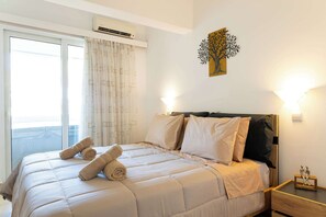 Una habitación de hotel con cama, mesita de noche, una obra de arte en la pared y una ventana con cortinas.