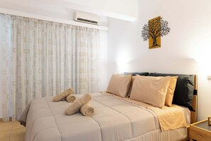 Une chambre à coucher avec un lit, des oreillers, un climatiseur fixé au mur et une œuvre d’art décorative accrochée au mur.