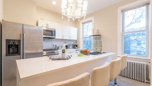 A modern kitchen with a central island, stainless steel appliances, and a chandelier.