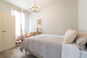 Une chambre à coucher comprenant un lit, une table de chevet, une chaise, une armoire et un lustre.