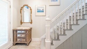 A staircase with white balusters, a wooden dresser with drawers, and a mirror with an ornate frame.