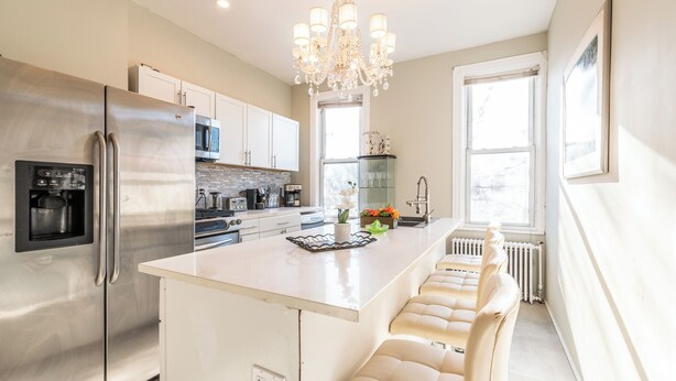 A modern kitchen with a large island, stainless steel appliances, and a chandelier.