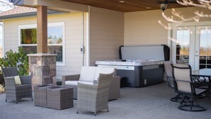 Een terras buiten met rieten meubels, een stenen pilaar en een hottub.