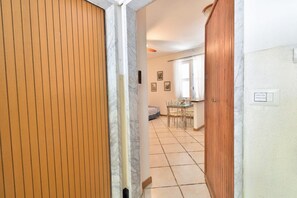 Un pasillo que conduce a un comedor con una mesa y sillas, una cama y una ventana con cortinas.