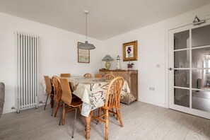 A dining area with a table set for four, a radiator, a cabinet, and a door with glass panels.