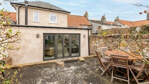 A house with a patio, a dining table, and chairs. - Devon Cottage | Elie (Elie)