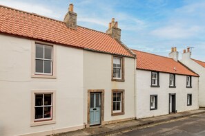 A row of white buildings with red-tiled roofs and multiple windows.