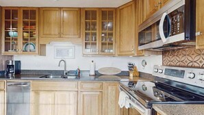 A kitchen with wooden cabinets, a stainless steel sink, a microwave, and a stove. - Bodega Bay 2BR ocean-view cottage with hot tub — dog friendly (Bodega Bay)