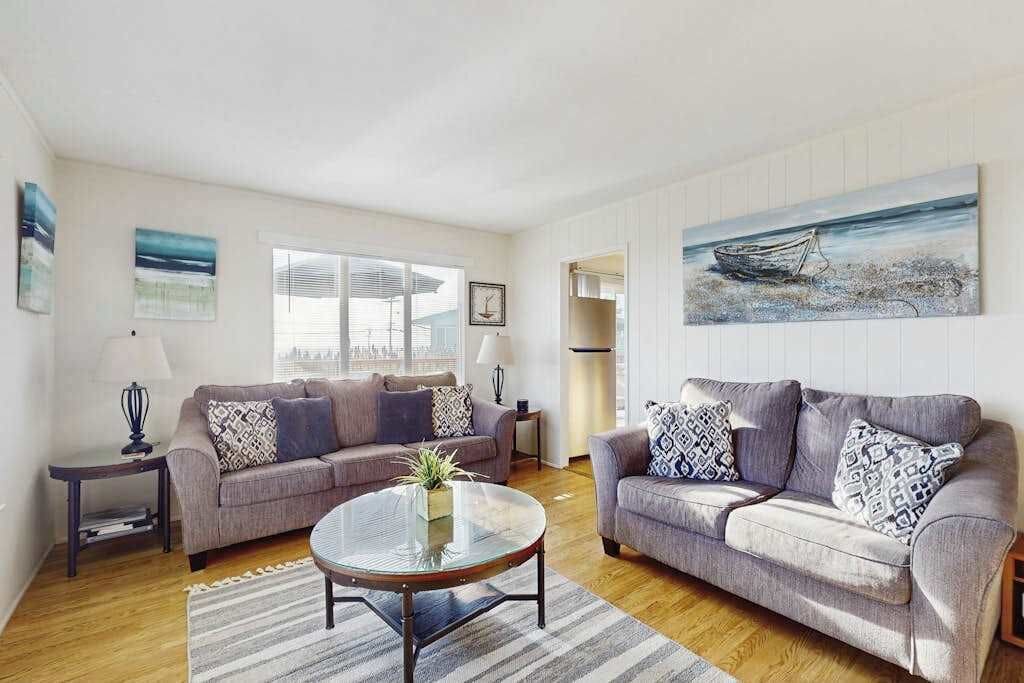 Sink into plush coastal-chic sofas surrounded by ocean-inspired artwork in your sunlit Bodega Bay living room — the perfect spot to unwind after a day exploring the Sonoma Coast.