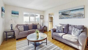A living room with two sofas, a coffee table, and a painting on the wall. - Bodega Bay 2BR ocean-view cottage with hot tub — dog friendly (Bodega Bay)