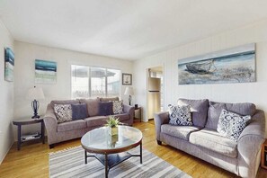 A living room with two sofas, a coffee table, and a painting on the wall.