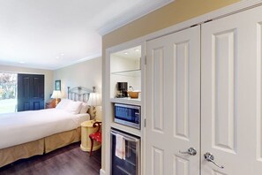 Ein Hotelzimmer mit Bett, Schreibtisch, Stuhl, Lampe, Fernseher, Mikrowelle und Kleiderschrank.