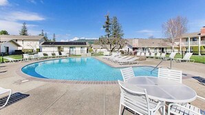 A swimming pool with lounge chairs and a table, surrounded by buildings. - Napa Silverado condo with private patio, hot tub & pool access (Napa)