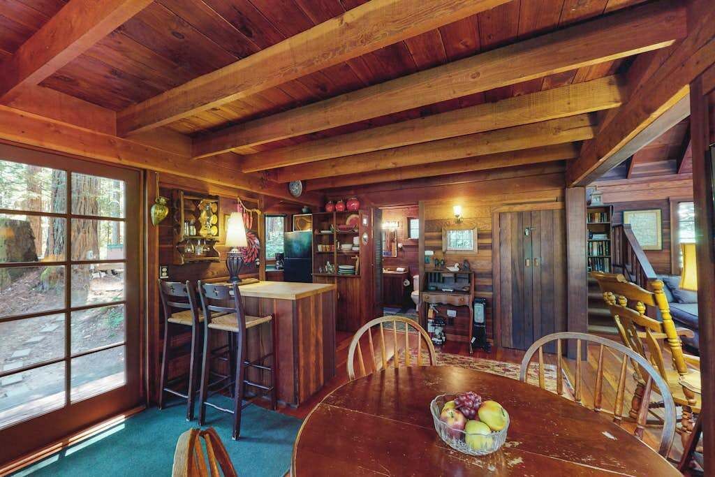 A rustic wooden interior with a dining area, bar, and bookshelves.