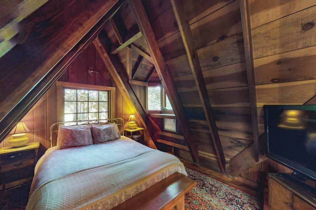 Ein Schlafzimmer im Dachgeschoss mit Bett, Fernseher und Fenster.