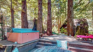 A wooden deck with a hot tub, a wooden bench, and a staircase leading to a cabin in a forest. - Cazadero 1BR A-frame cabin with hot tub for two — dog friendly (Cazadero)