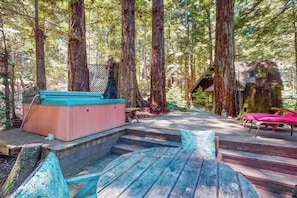 A wooden deck with a hot tub, a wooden bench, and a staircase leading to a cabin in a forest. - Cazadero 1BR A-frame cabin with hot tub for two — dog friendly (Cazadero)