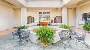 A courtyard with a central fountain, surrounded by outdoor seating and potted plants.