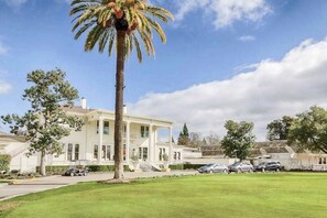 A large, white building with a covered porch, surrounded by a well-maintained lawn and parked cars. - Napa 1BR Silverado Trail condo with fireplace, pool & EV charger (Napa)