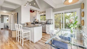 A modern kitchen with white cabinetry, a central island, and a glass dining table.