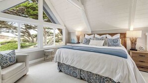 A bedroom with a large bed, a window, and a view of trees.