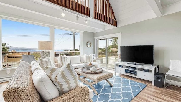 A spacious living room with a large TV, comfortable seating, and a view of the outdoors.