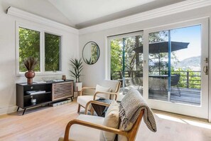 A spacious living room with a large sliding glass door leading to an outdoor deck, a modern fireplace, and a minimalist decor style. - Cloverdale Dog-Friendly Pool Retreat near Wineries (Cloverdale)