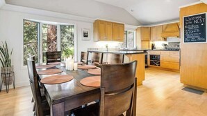 Uma cozinha moderna com armários de madeira, uma ilha central e um espaço de refeições com mesa e cadeiras.