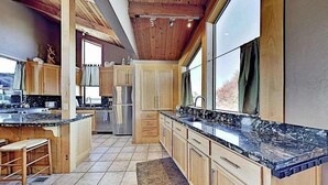 Una cocina con armarios de madera, encimera de granito y refrigerador.