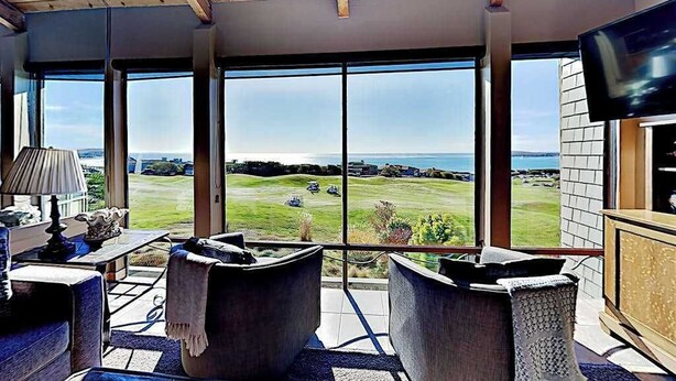 Una habitación con ventanas amplias, televisor y vista a un campo de golf.