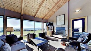 Una sala de estar moderna con un ventanal grande, una chimenea y una zona de estar.