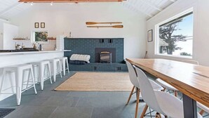 Eine moderne Küche mit Kamin, weißen Barhocker und einem Holzessttisch.