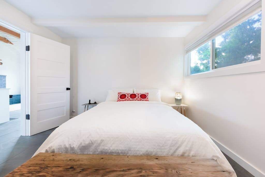 Ein Schlafzimmer mit einem Bett, einer hölzernen Bank, einem Nachttisch und einem Fenster.