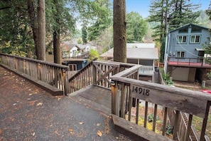 A wooden deck with a railing, a house number 14918, and a forested background.