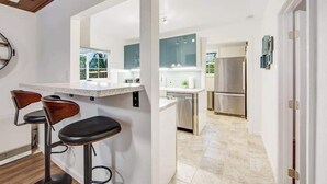 Une cuisine moderne avec un coin bar, des appareils en acier inoxydable et une vue par la fenêtre.